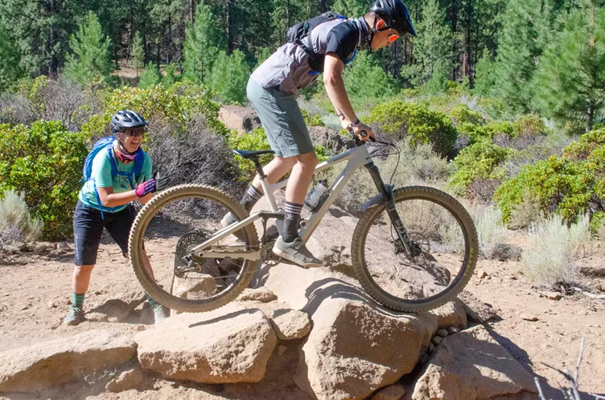 Learning to mountain bike over a rock obstacle with Grit Clinic's Professional MTB Skills Coach