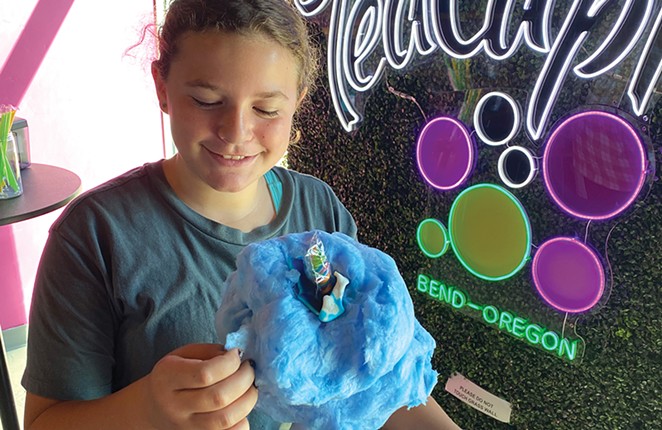 Tween looks at cotton candy on top of drink