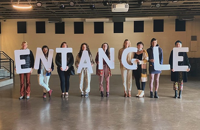 People hold "Entangle" written in individual letters