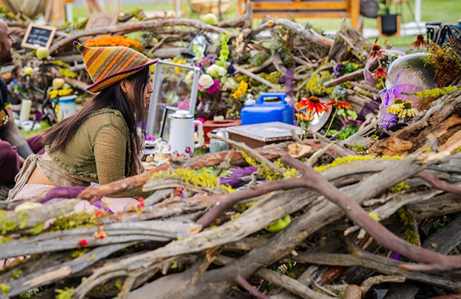 Person dressed as a gnome inside a wooden nest